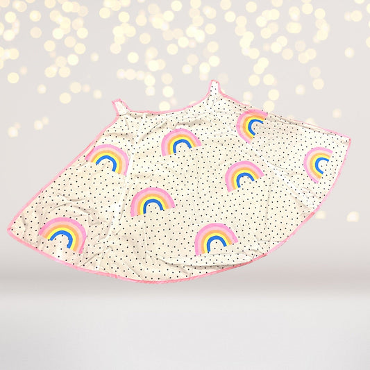 Light-colored children's costume cape printed with small rainbows and dotted details, with pink edging.